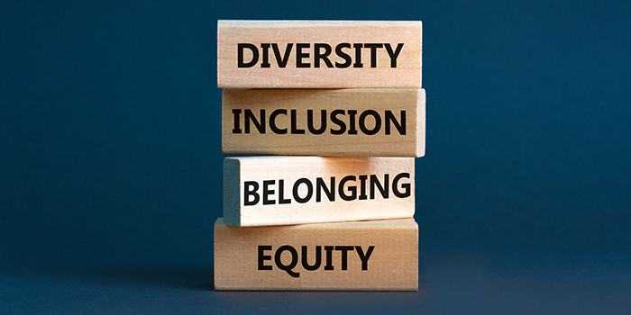 Photograph of wood blocks on a dark blue backdrop with words DIVERSITY INCLUSION BELONGING EQUITY printed on each block