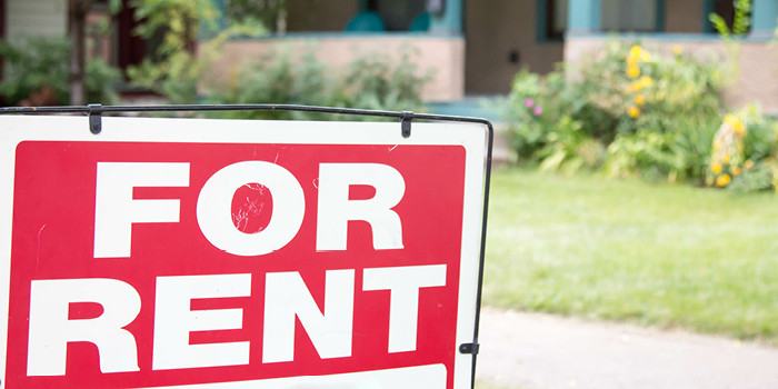 Photograph of red FOR RENT sign in front of green lawn