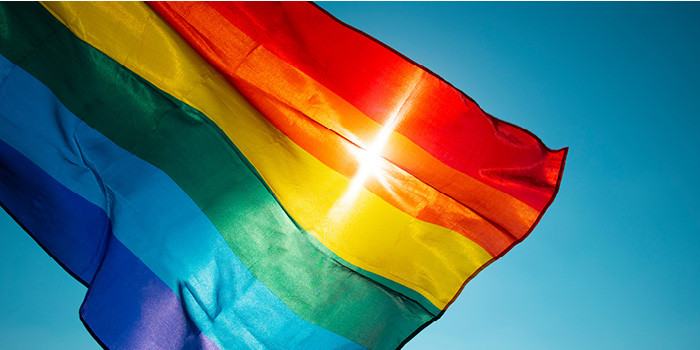 Photo of rainbow flag with sun and blue sky